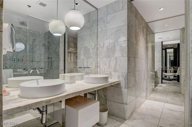 bathroom with tiled shower, tile walls, and sink