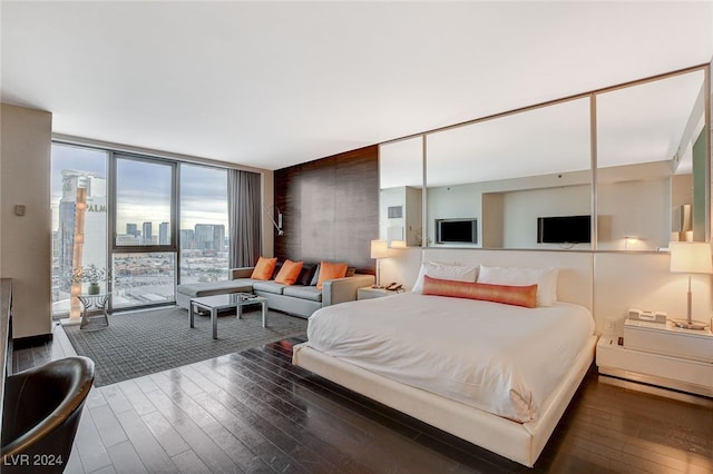 bedroom with a wall of windows and dark wood-type flooring