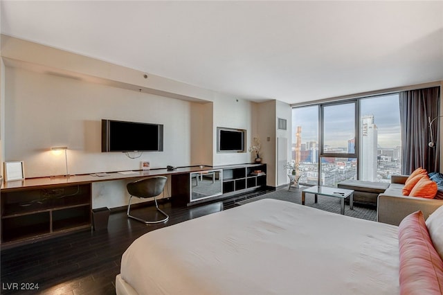 bedroom with expansive windows and dark hardwood / wood-style floors