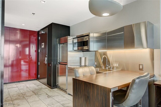 kitchen with kitchen peninsula, a kitchen bar, stainless steel appliances, and sink