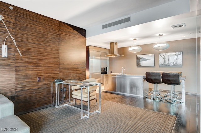 kitchen with sink, dark wood-type flooring, wood walls, and exhaust hood