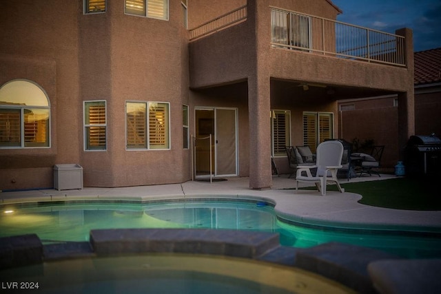 back of house featuring a balcony, a patio, and a pool with hot tub