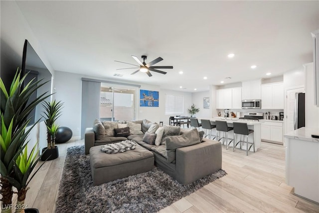 living room with ceiling fan and light wood-type flooring