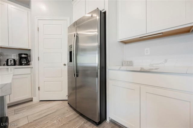 kitchen with white cabinets, stainless steel fridge with ice dispenser, and light hardwood / wood-style flooring