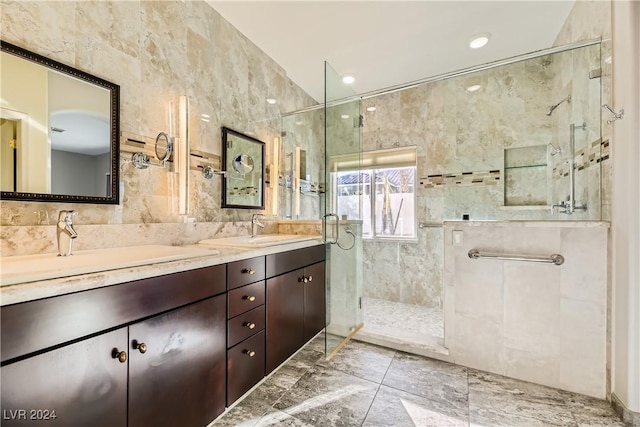 bathroom with a sink, a shower stall, double vanity, and tile walls