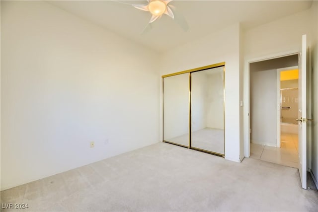 unfurnished bedroom with a closet, light colored carpet, and ceiling fan