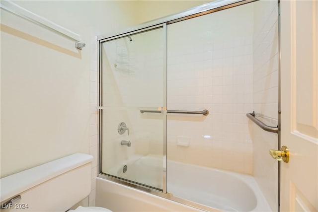 bathroom with combined bath / shower with glass door and toilet