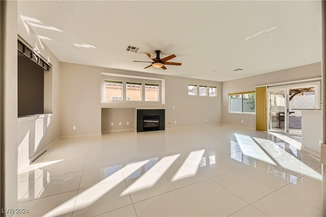 unfurnished living room featuring a fireplace, ceiling fan, and light tile patterned flooring