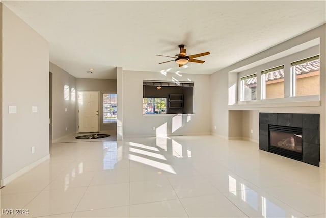 unfurnished living room featuring a tiled fireplace, ceiling fan, and tile patterned flooring