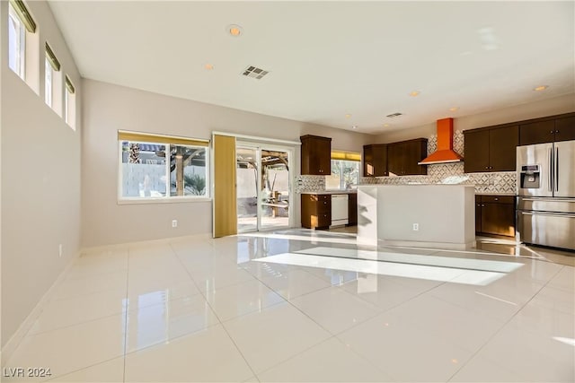 kitchen featuring light tile patterned flooring, dishwasher, wall chimney exhaust hood, stainless steel fridge, and tasteful backsplash