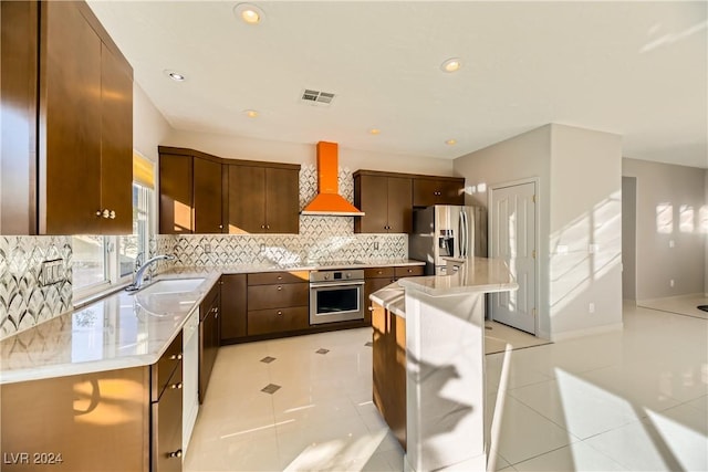 kitchen featuring sink, backsplash, premium range hood, a kitchen island, and stainless steel appliances