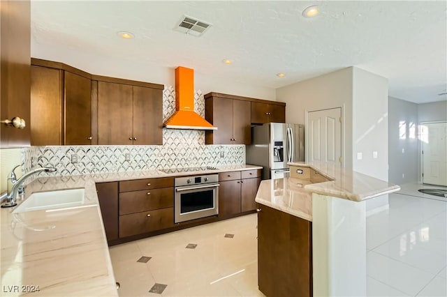 kitchen with appliances with stainless steel finishes, premium range hood, a center island, backsplash, and sink