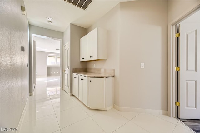 corridor featuring light tile patterned floors, baseboards, and visible vents