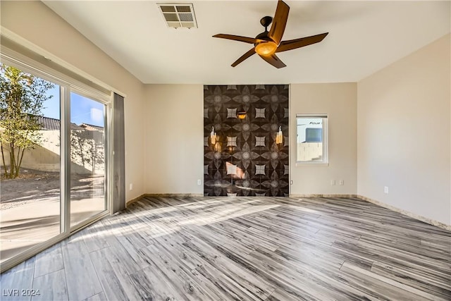 unfurnished room with visible vents, ceiling fan, baseboards, and wood finished floors