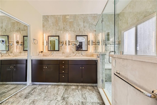 full bathroom featuring double vanity, a stall shower, and a sink