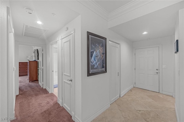 corridor with ornamental molding and light carpet