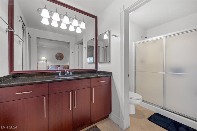 bathroom with an enclosed shower, vanity, toilet, and tile patterned flooring