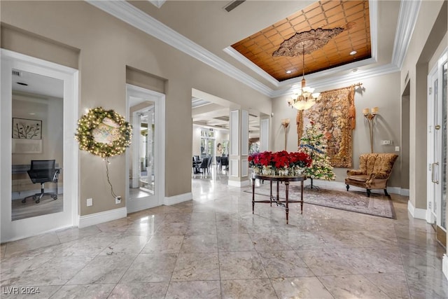 interior space with a chandelier, a tray ceiling, and crown molding