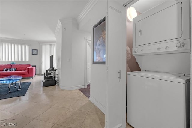 laundry area featuring ornamental molding, light tile patterned floors, and stacked washer and clothes dryer