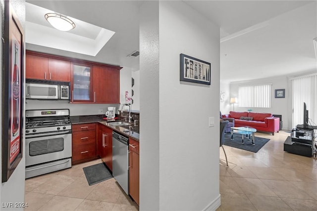 kitchen with a raised ceiling, sink, light tile patterned floors, and stainless steel appliances