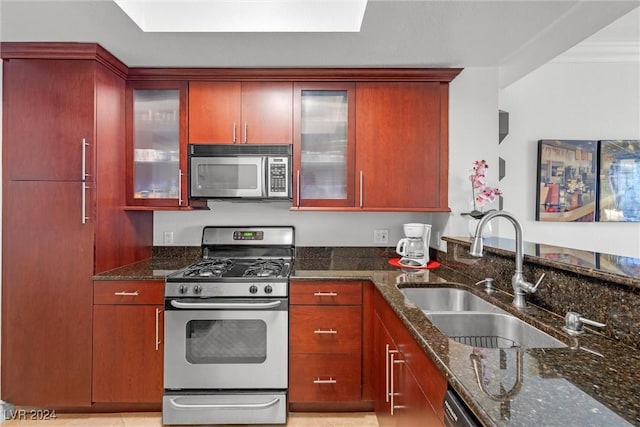 kitchen with stainless steel appliances, crown molding, dark stone countertops, and sink