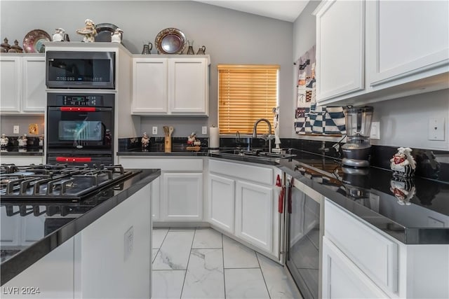 kitchen with lofted ceiling, sink, wine cooler, double oven, and white cabinetry