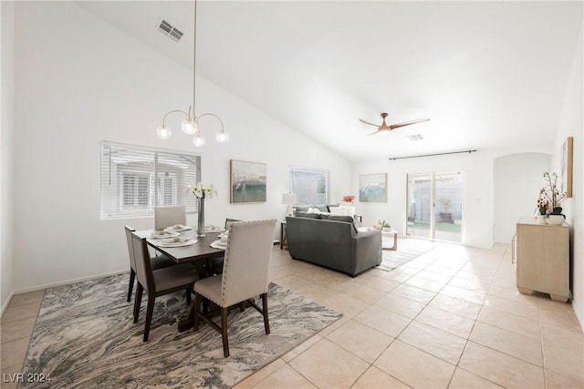 tiled dining space with ceiling fan with notable chandelier, vaulted ceiling, and a healthy amount of sunlight