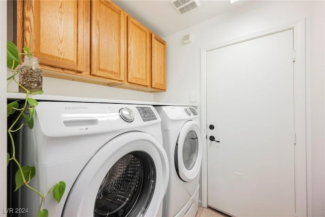 clothes washing area with cabinets and separate washer and dryer