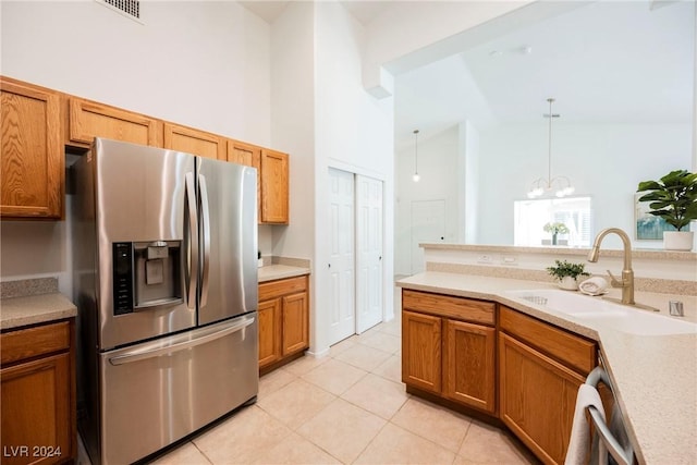 kitchen featuring pendant lighting, high vaulted ceiling, sink, stainless steel fridge, and light tile patterned floors