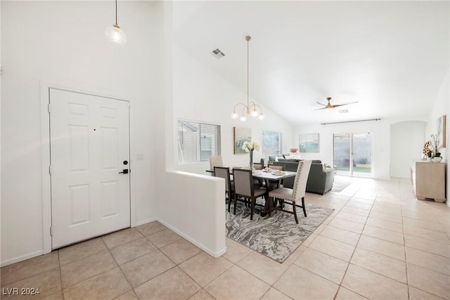 entrance foyer featuring ceiling fan with notable chandelier, light tile patterned flooring, and high vaulted ceiling