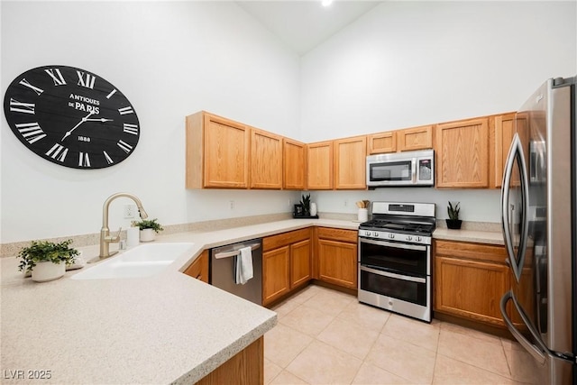 kitchen featuring kitchen peninsula, a towering ceiling, sink, and appliances with stainless steel finishes