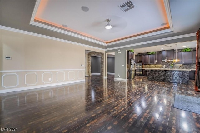 unfurnished living room with dark hardwood / wood-style floors, crown molding, and a tray ceiling