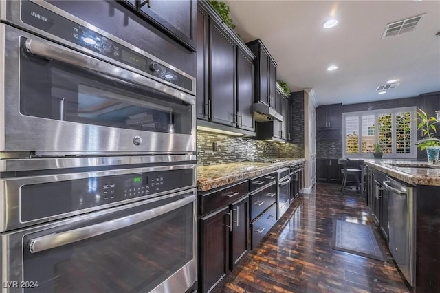 kitchen featuring sink, tasteful backsplash, dark brown cabinets, light stone counters, and stainless steel appliances