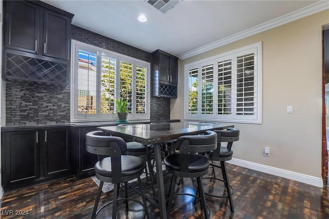 dining room with a healthy amount of sunlight, ornamental molding, and dark wood-type flooring