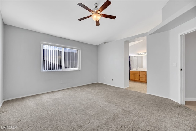 unfurnished bedroom featuring ceiling fan, light colored carpet, and ensuite bath