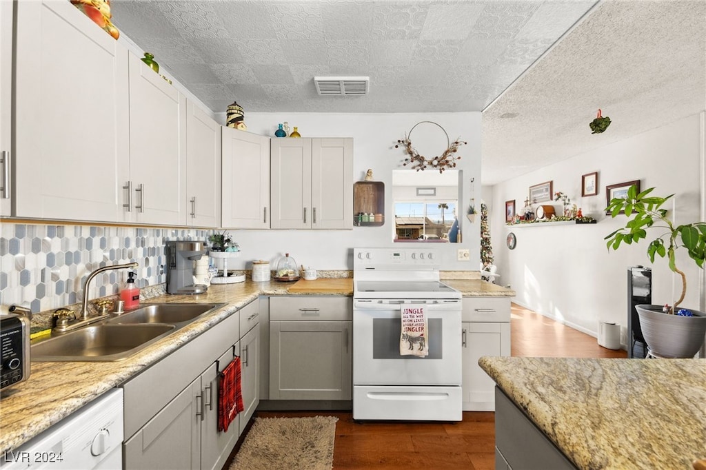 kitchen featuring sink, tasteful backsplash, dark hardwood / wood-style floors, white appliances, and gray cabinets