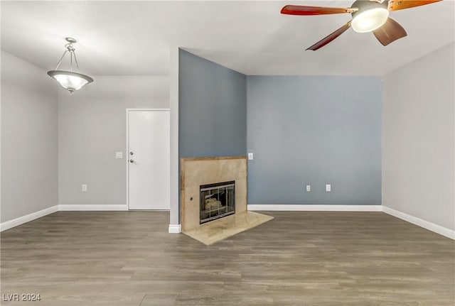 unfurnished living room featuring hardwood / wood-style floors, ceiling fan, and a tiled fireplace