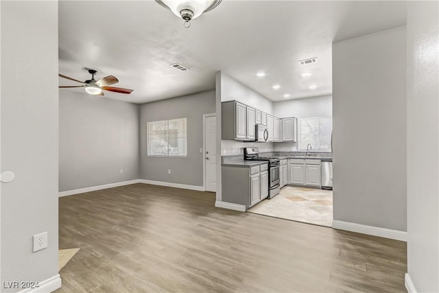 kitchen with ceiling fan, sink, stainless steel appliances, light hardwood / wood-style floors, and gray cabinets