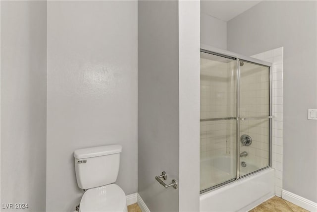 bathroom with shower / bath combination with glass door, tile patterned floors, and toilet