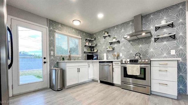 kitchen with light wood-type flooring, stainless steel appliances, white cabinetry, and wall chimney exhaust hood