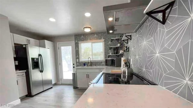 kitchen featuring white cabinets, plenty of natural light, sink, and stainless steel refrigerator with ice dispenser