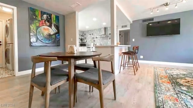 dining space with stacked washer and dryer and light hardwood / wood-style flooring