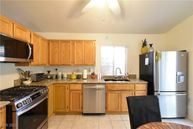 kitchen featuring light stone counters, stainless steel appliances, ceiling fan, sink, and light tile patterned flooring