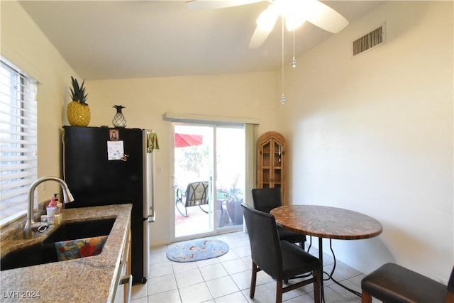 kitchen with refrigerator, light stone counters, ceiling fan, sink, and light tile patterned flooring