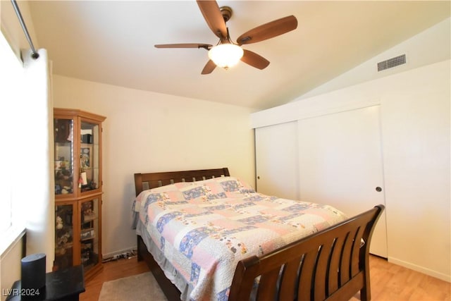 bedroom with a closet, ceiling fan, light hardwood / wood-style flooring, and vaulted ceiling