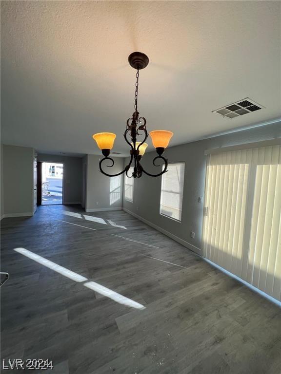 unfurnished dining area featuring dark hardwood / wood-style flooring and a notable chandelier