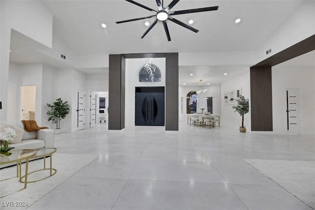 living room with ceiling fan with notable chandelier and a towering ceiling