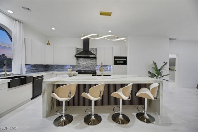 kitchen with sink, wall chimney exhaust hood, stainless steel dishwasher, decorative light fixtures, and a kitchen island