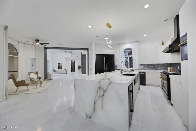 kitchen featuring wall chimney exhaust hood, premium appliances, a spacious island, white cabinets, and hanging light fixtures