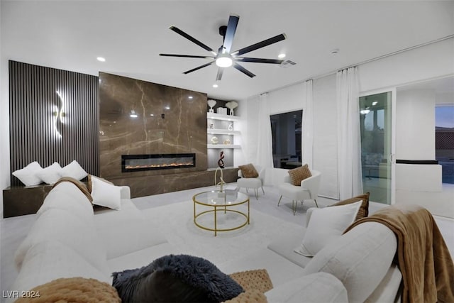 living room featuring built in shelves, a premium fireplace, and ceiling fan